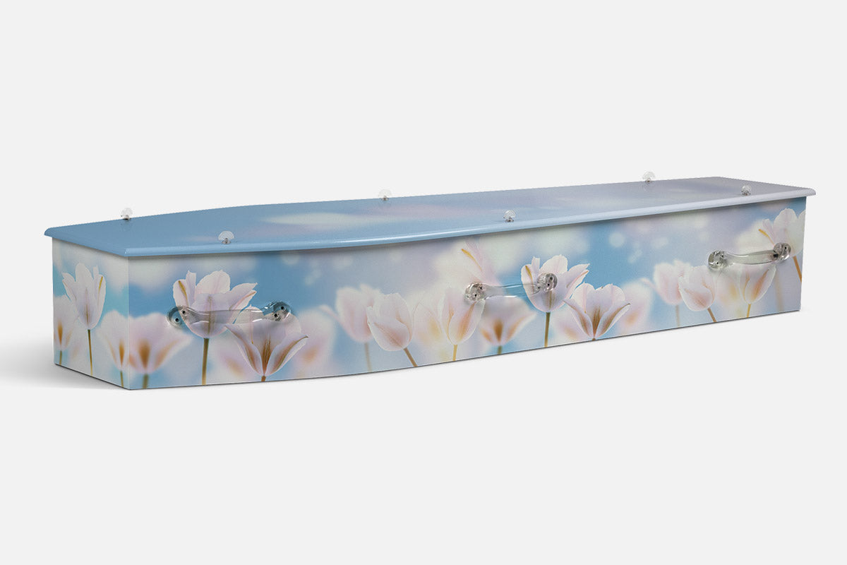 Blooming Tulip coffin in pale pink and white tulips against a soft blue sky