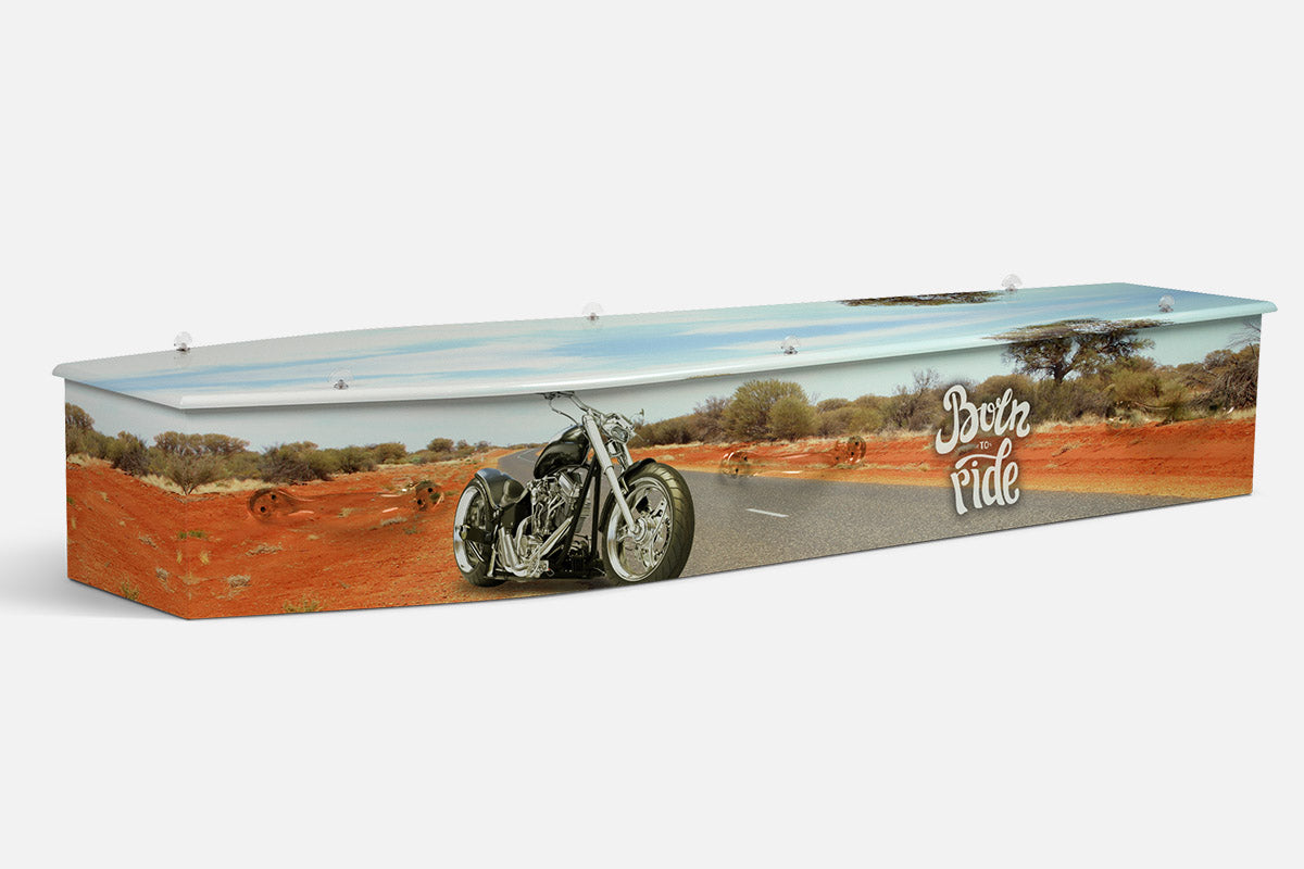Born To Ride coffin in an outback scene with a black chopper motorcycle and Born To Ride script