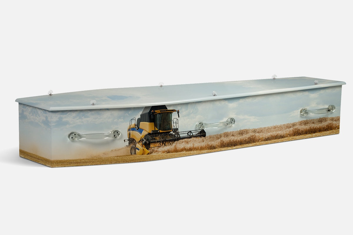 Harvest coffin showing a yellow combine harvester cutting wheat in a pale golden field under a soft sky