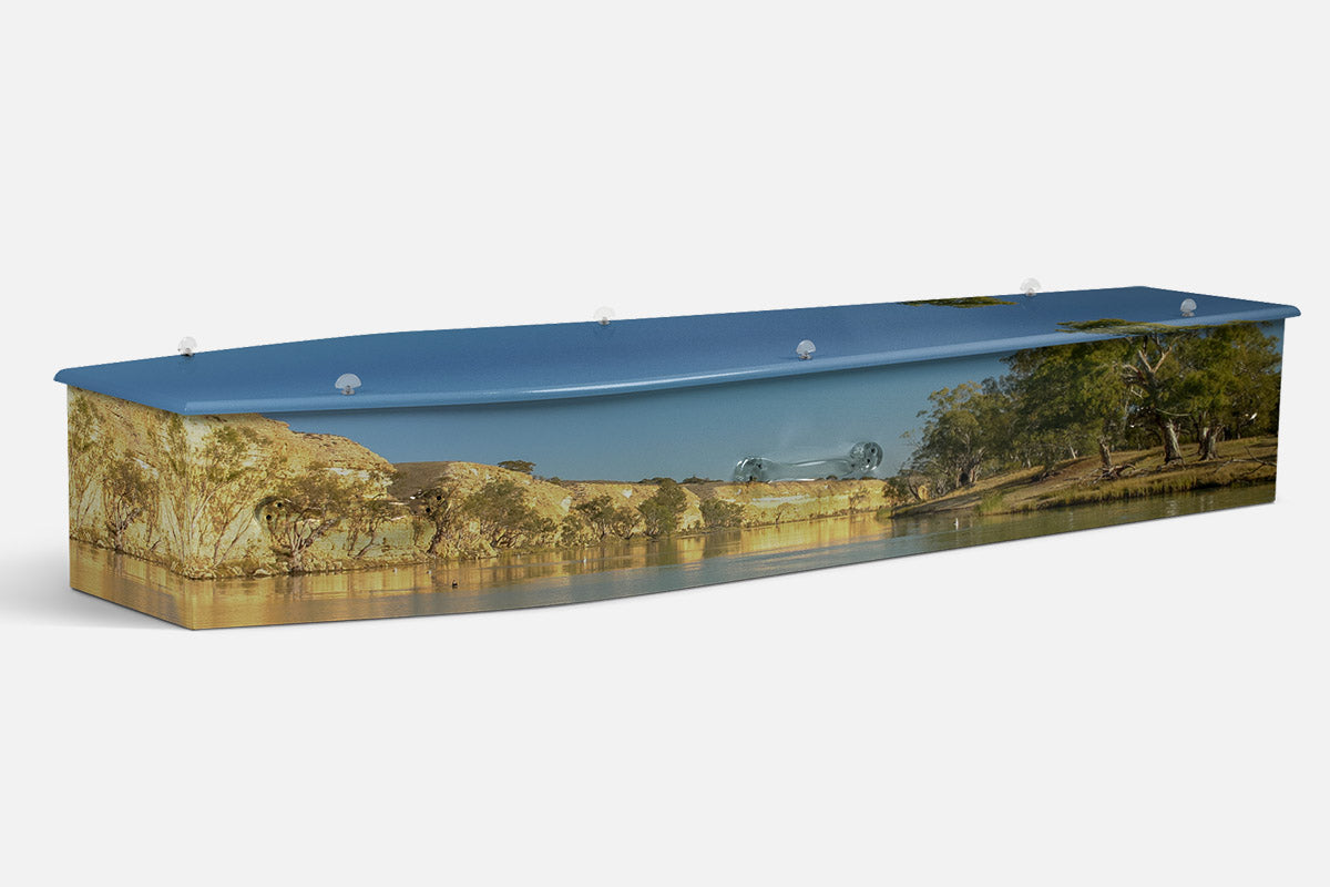 Murray River coffin in a photographic scene of green gum trees lining a still, mirror like river