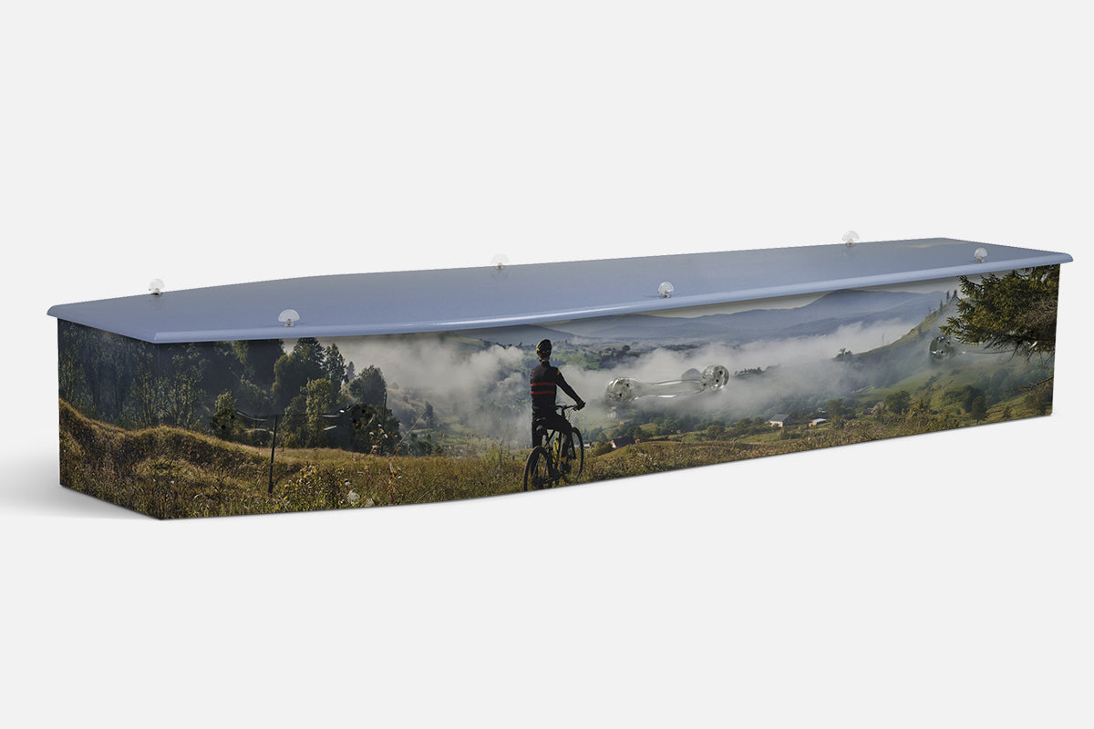 Mountain Biking coffin with a rider pausing on a misty green mountainside trail