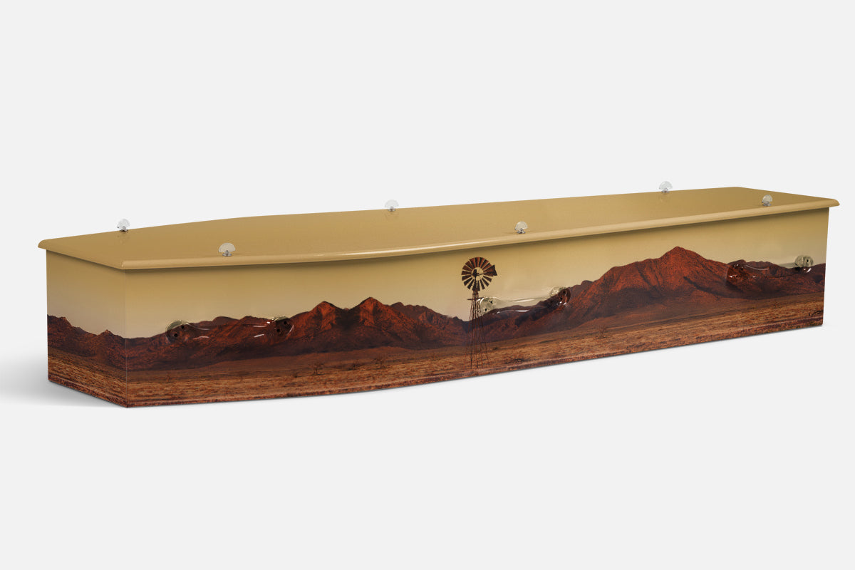 Sunset Outback coffin in red desert ranges with a windmill under a pale sky, photographic