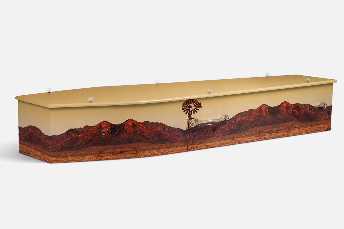 Sunset Ranges coffin in red mountain ranges and a windmill across an outback plain