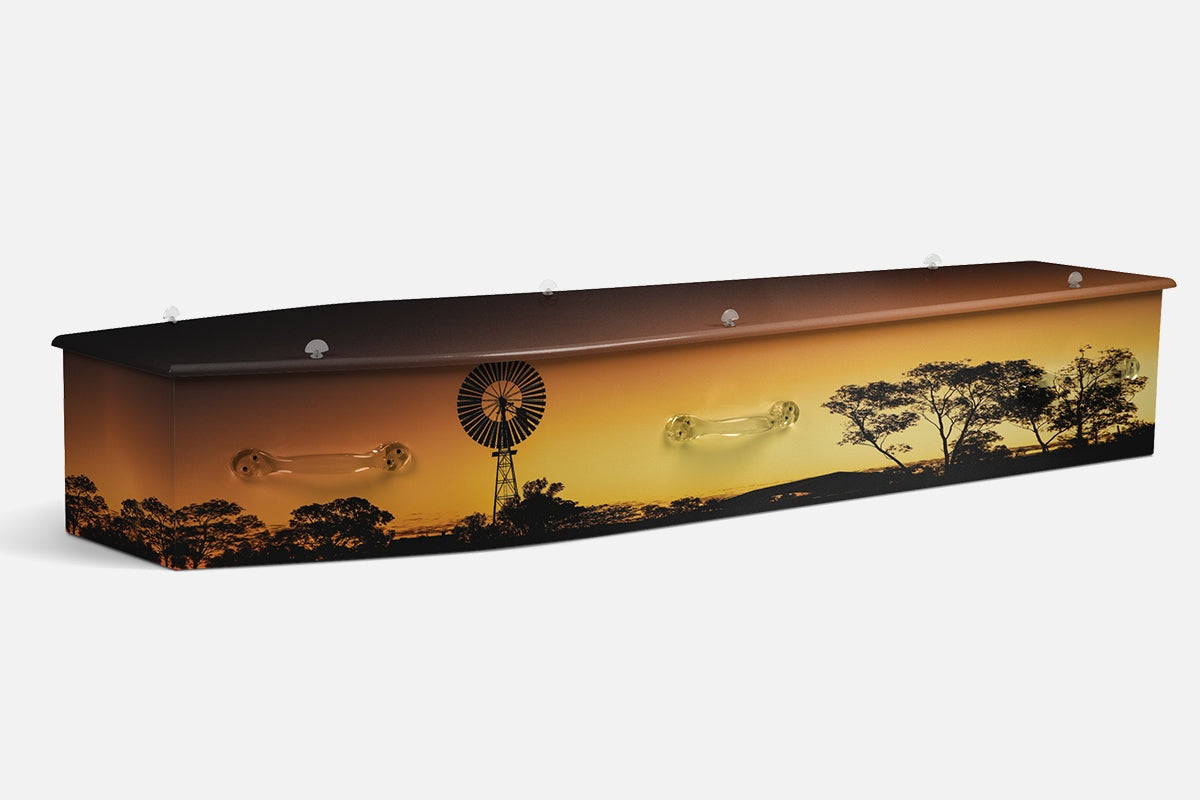 Sunset Windmill coffin in silhouette with a farm windmill, gum trees and a glowing orange sky
