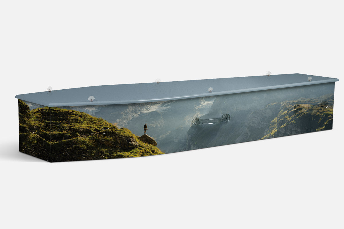 The Hiker coffin in a photographic misty mountain scene with a hiker standing on a moss covered rocky slope